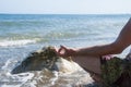 Young manÃ¢â¬â¢s hand doing yoga on a beach. Man sitting on a rock by the sea. Summer vacation. Mediterranean Sea.